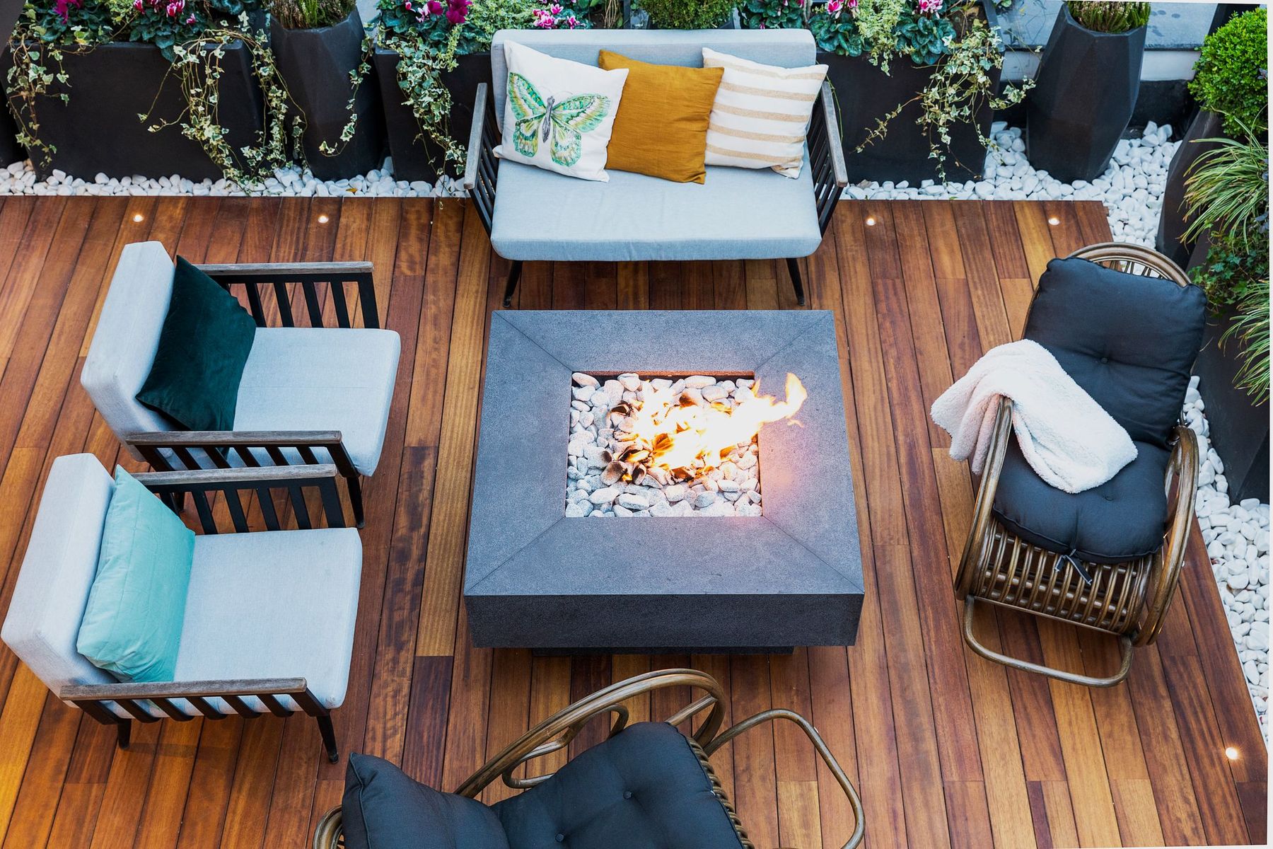 A warmly lit outdoor living space at dusk with a fire burning